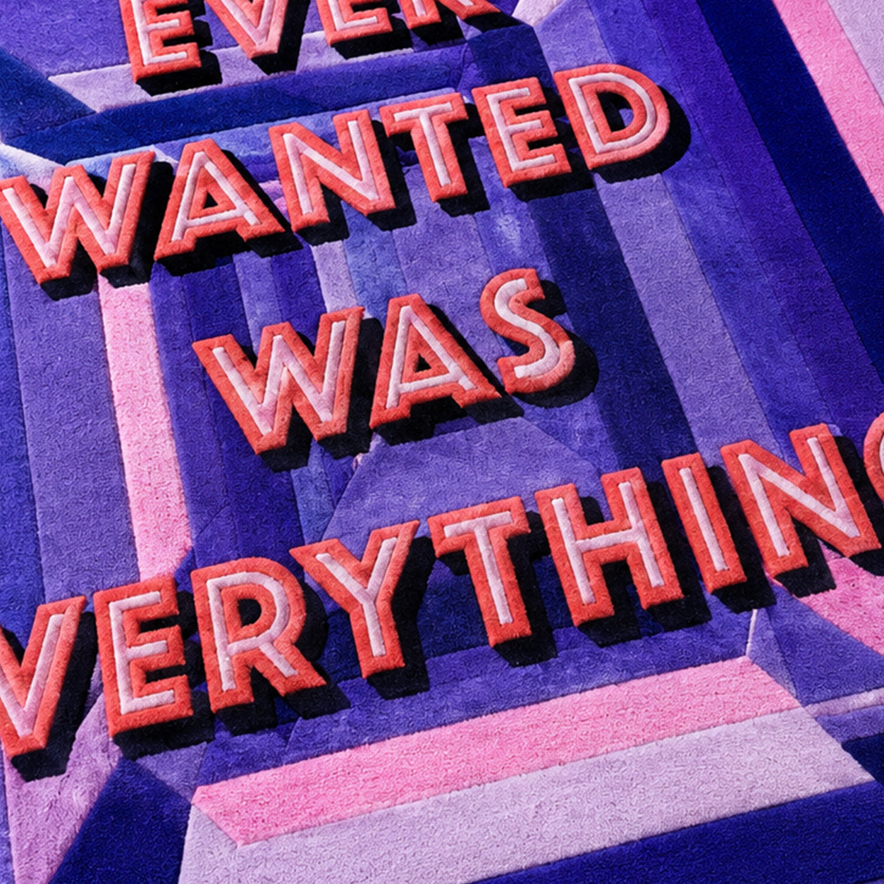 Close-up of the tufted lettering on the All I Ever Wanted Was Everything Gem Rug in purple and coral pink