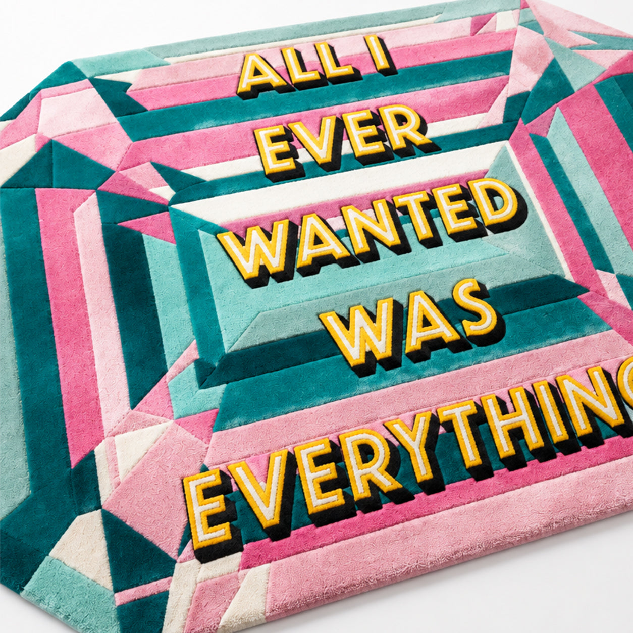 Close-up of the yellow tufted lettering on the pink and teal All I Ever Wanted Was Everything Pastel Gem Rug