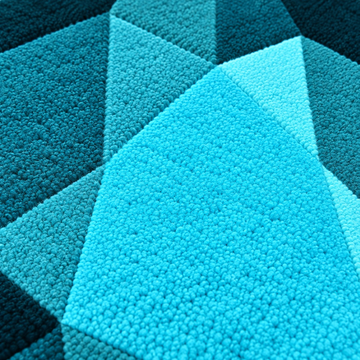Close-up of the facets on the Turquoise Drop Gem Rug running from deep teal to a pale white flash at the point